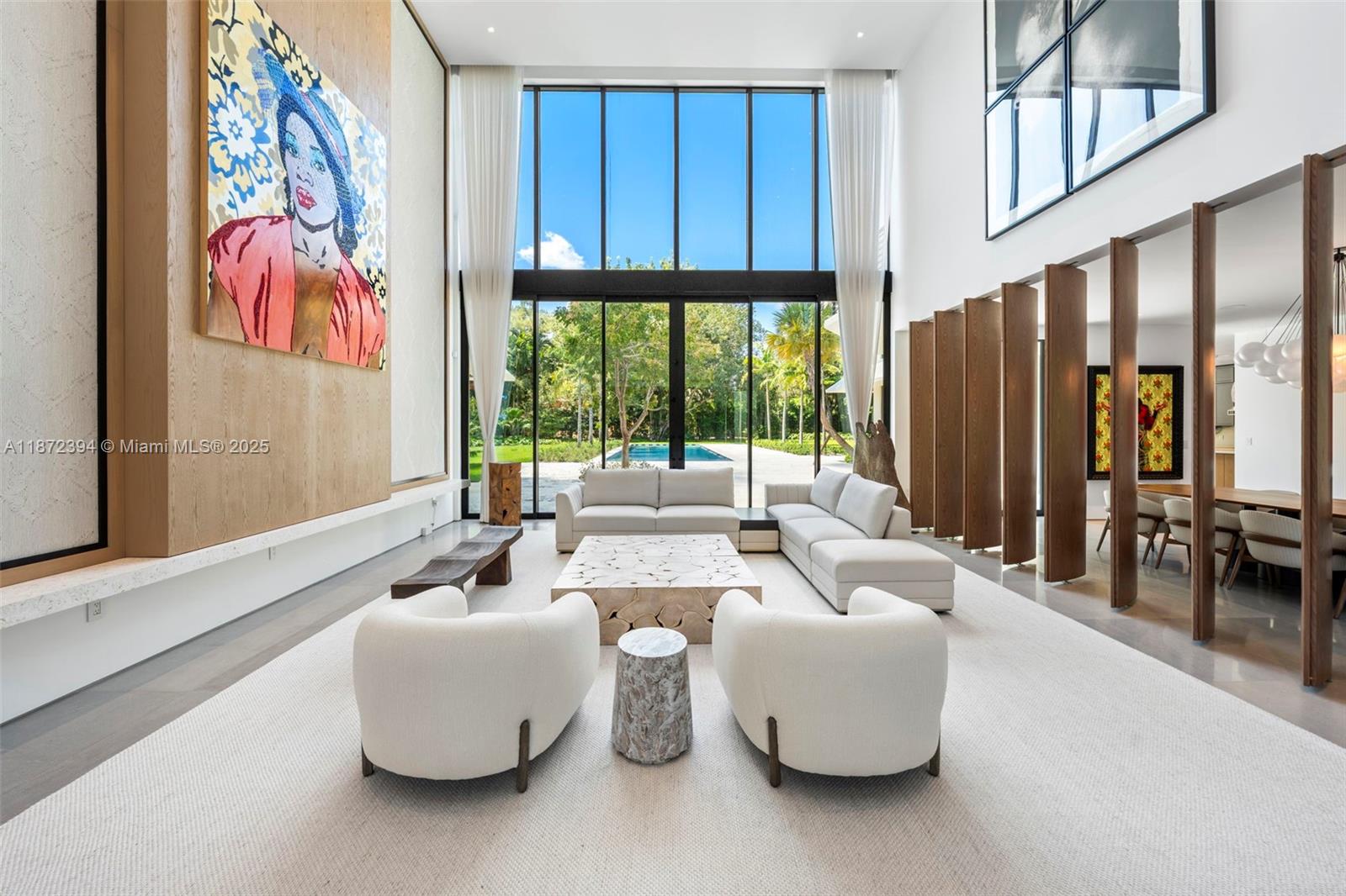 A spacious living room features double-height windows, a large abstract painting, and modern white furniture — 9440 Old Cutler Ln, Coral Gables FL 33156, CORAL GABLES, FL