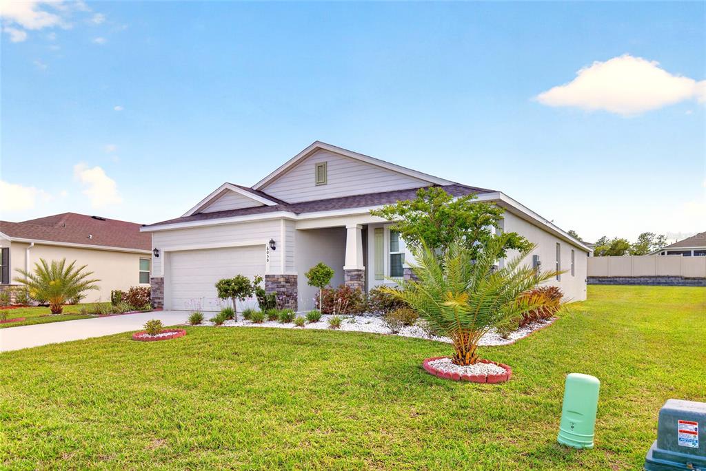 A single-story suburban house with a two-car garage, stone accents, and a landscaped front yard — 6050 SW 93RD LOOP, OCALA, FL