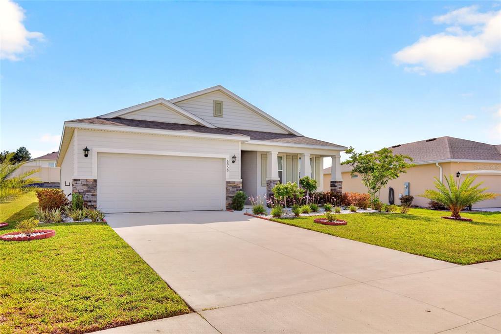 A single-story suburban house with a two-car garage, stone accents, and a concrete driveway — 6050 SW 93RD LOOP, OCALA, FL