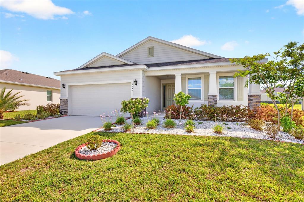 A single-story suburban house with a two-car garage, stone accents, and a landscaped front yard — 6050 SW 93RD LOOP, OCALA, FL