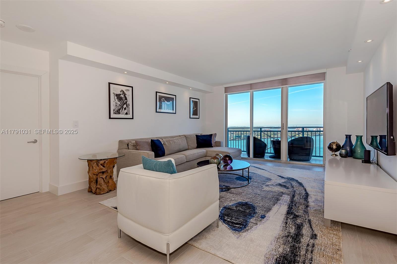 A living room features a sectional sofa, white armchair, area rug, and a balcony view — 90 Alton Rd # 2410, Miami Beach FL 33139, MIAMI BEACH, FL