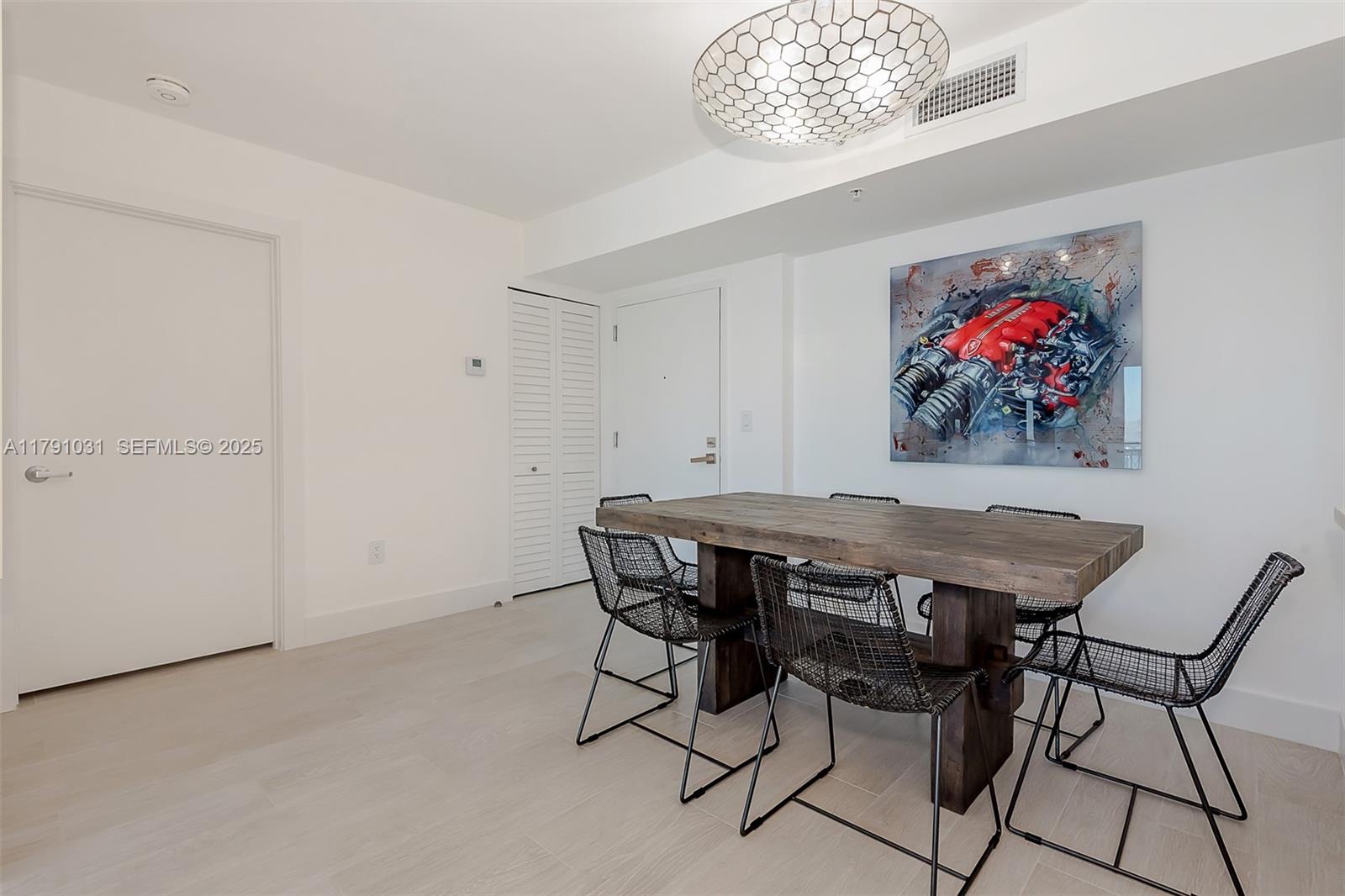 A dining room features a wooden table, black wire chairs, and a large engine artwork — 90 Alton Rd # 2410, Miami Beach FL 33139, MIAMI BEACH, FL