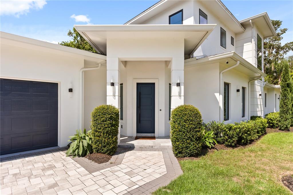 A modern white house exterior features a dark blue front door and garage door — 3125 S BUMBY AVENUE, ORLANDO, FL