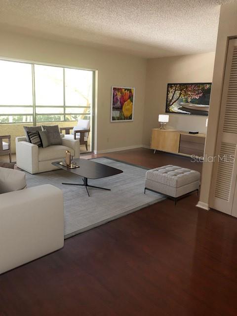 A living room features a white armchair, a coffee table, and a light-colored area rug — 13612 SOUTH VILLAGE DRIVE UNIT 5-207, TAMPA, FL