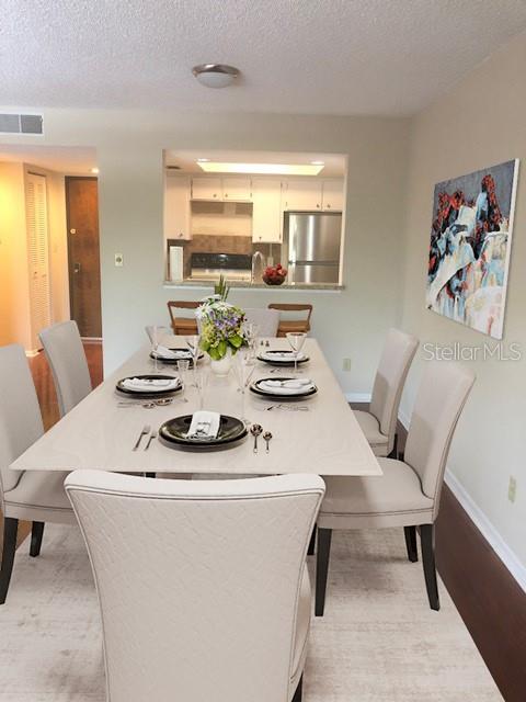 A dining room features a light-colored table with six chairs and a view into the kitchen — 13612 SOUTH VILLAGE DRIVE UNIT 5-207, TAMPA, FL