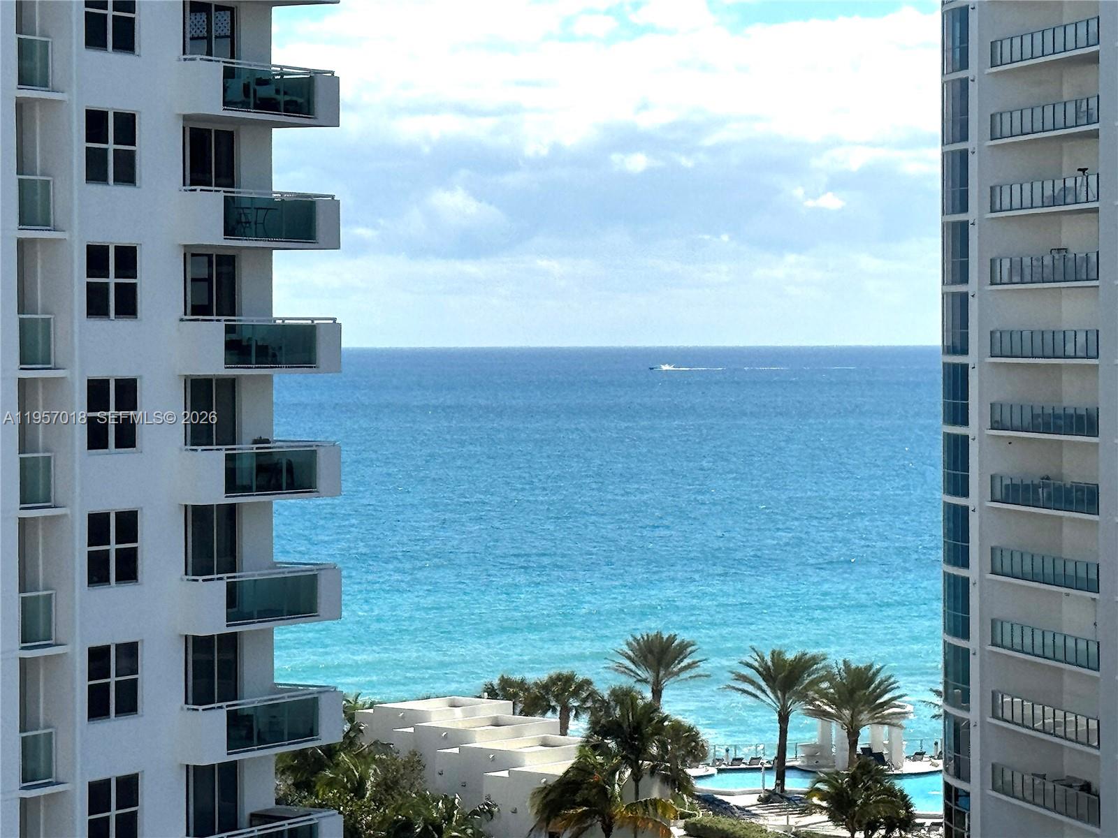 A living room features a dark sofa, a teal chair, and a view of buildings — 3000 S OCEAN DR # 1006, Hollywood FL 33019, HOLLYWOOD, FL