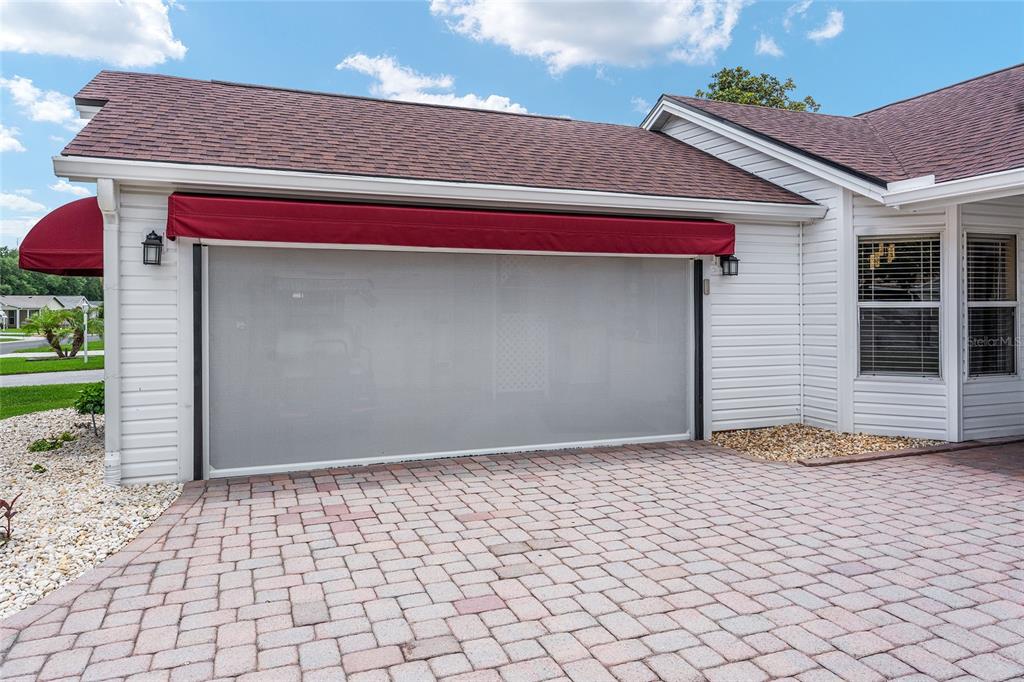 A house exterior features a garage with a retractable screen door and a paved driveway — 736 CORTEZ AVENUE, THE VILLAGES, FL
