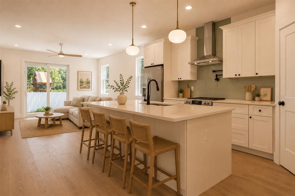 A modern kitchen with white cabinetry, a large island, and an open-concept living area — 7617 ALVINA STREET, TAMPA, FL