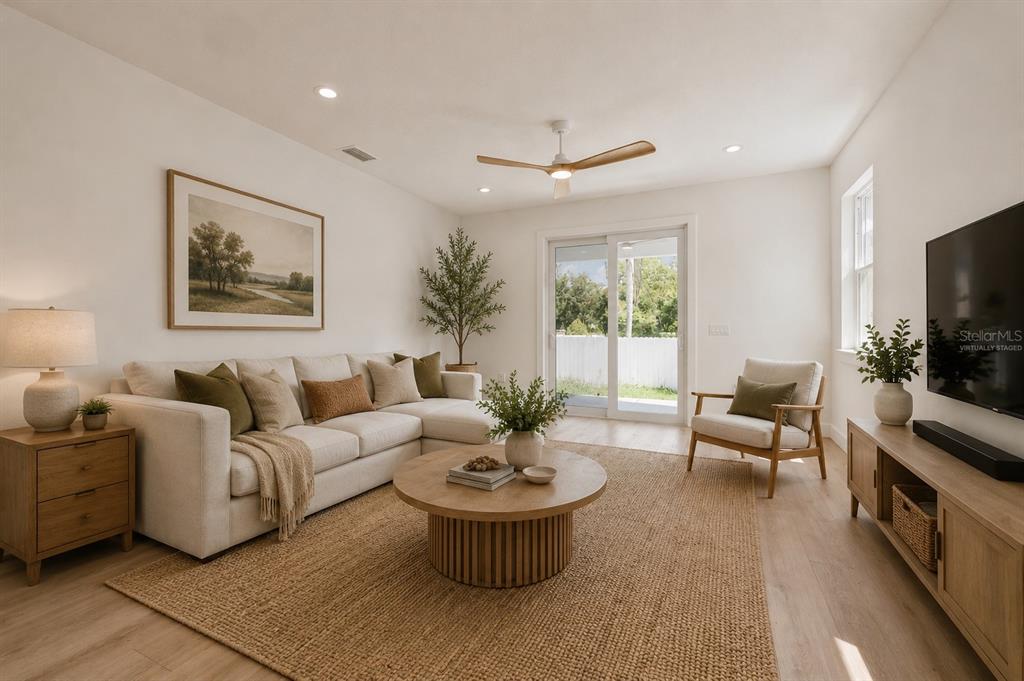 A living room with a sectional sofa, round coffee table, and sliding glass doors — 7617 ALVINA STREET, TAMPA, FL