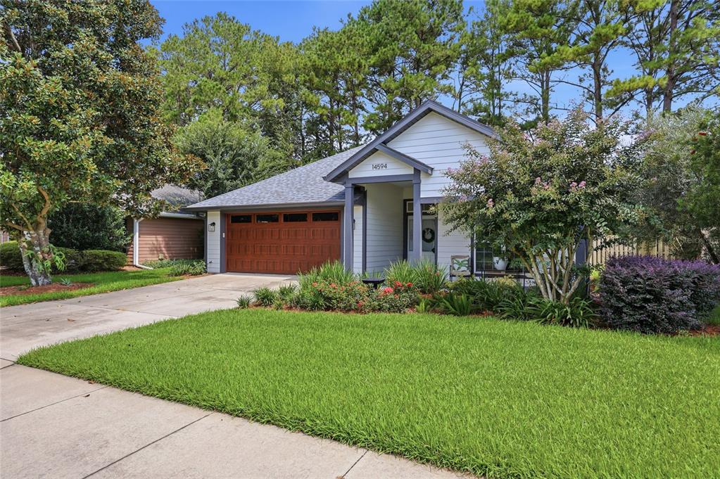 A single-story house with a white exterior, a brown garage door, and a grassy front yard — 14594 NW 25TH AVENUE, NEWBERRY, FL
