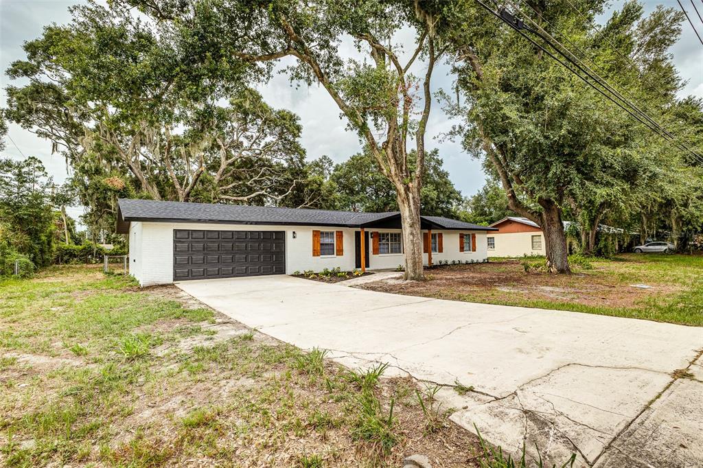 A white brick ranch house features a dark garage door and a concrete driveway — 5421 LAKE LUTHER ROAD, LAKELAND, FL
