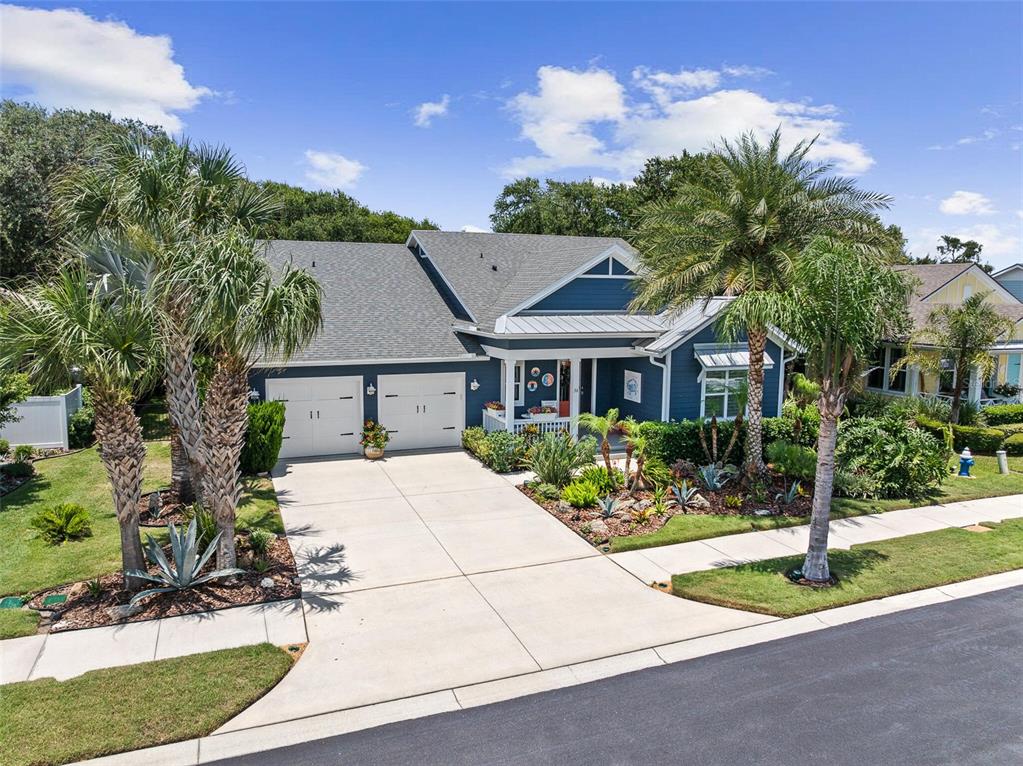 A blue single-story house features a two-car garage, a front porch, and palm trees — 36 HIDDEN TREASURE DRIVE, PALM COAST, FL