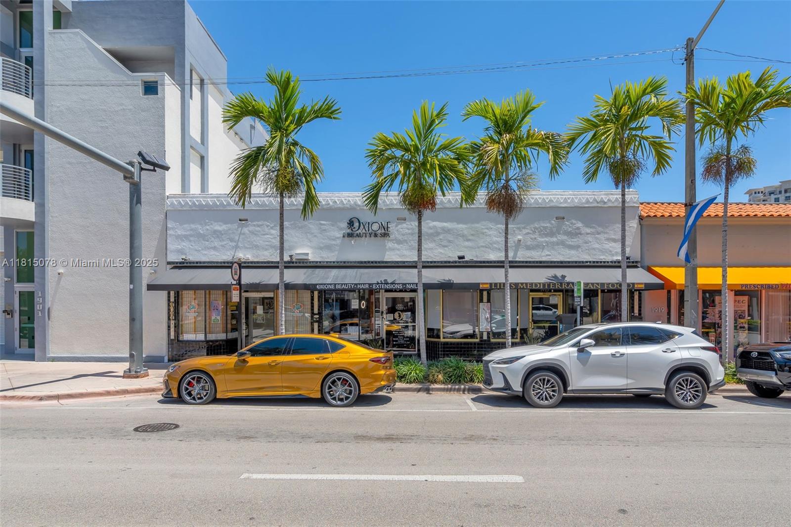 A street-level view of a commercial building with palm trees and parked cars in front — 1913 Ponce De Leon Blvd, Coral Gables FL 33134, CORAL GABLES, FL