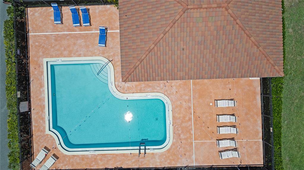 An aerial view shows an L-shaped swimming pool surrounded by a patio with lounge chairs — 3455 COUNTRYSIDE BOULEVARD UNIT 11, CLEARWATER, FL