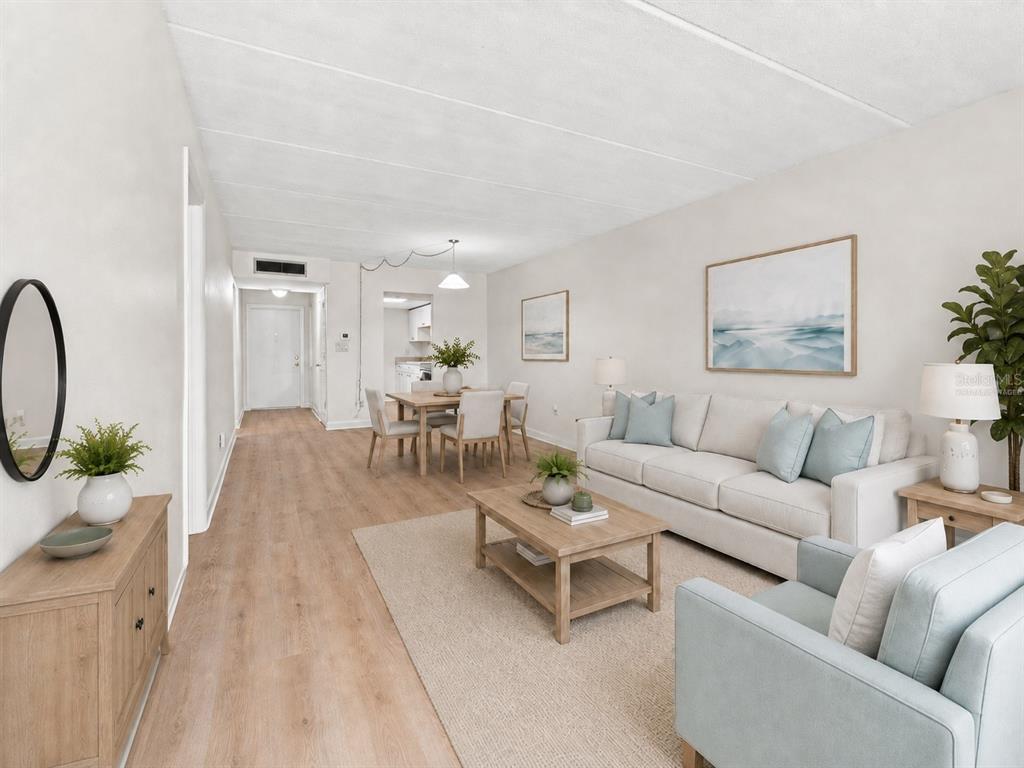 A living room and dining area feature light wood flooring, a sofa, and neutral decor — 4435 1ST STREET NE UNIT 110, ST PETERSBURG, FL