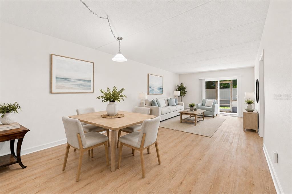 A bright open-concept living and dining area features light wood flooring and a sliding glass door — 4435 1ST STREET NE UNIT 110, ST PETERSBURG, FL