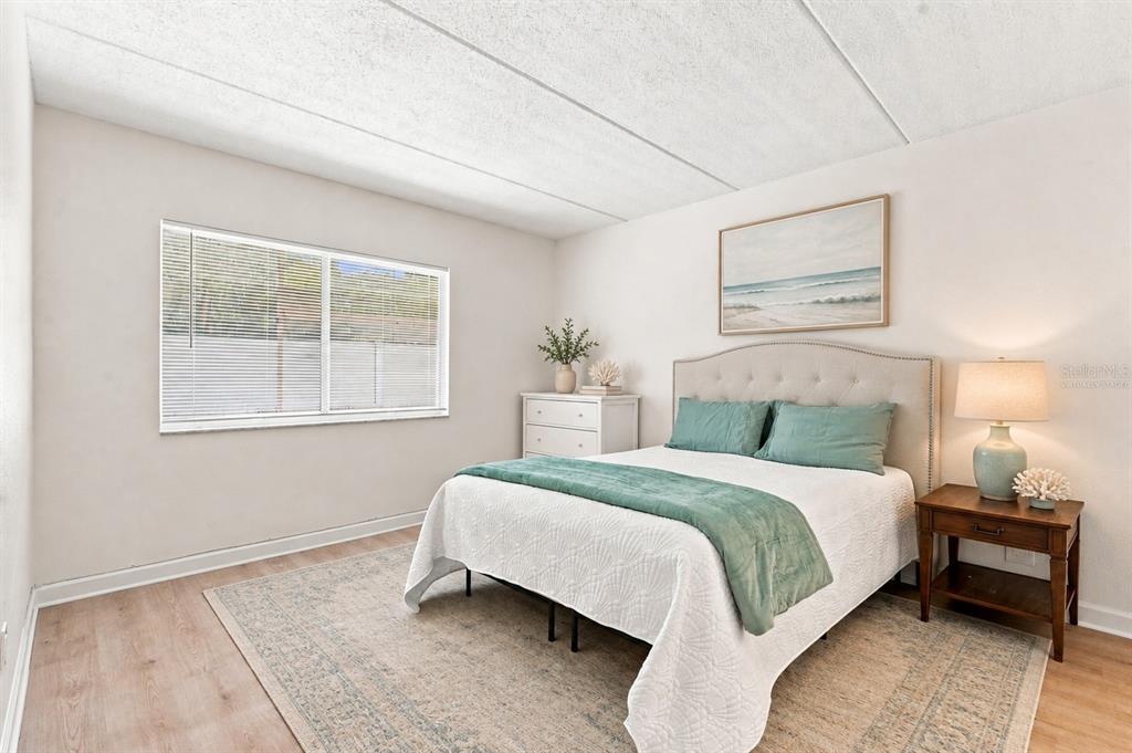 A bedroom features a queen bed with teal bedding, a white dresser, and a nightstand — 4435 1ST STREET NE UNIT 110, ST PETERSBURG, FL
