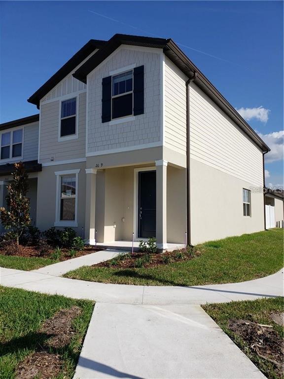 A two-story house with beige siding and a covered front entrance under a clear sky — 2659 MEAD AVENUE, ST CLOUD, FL