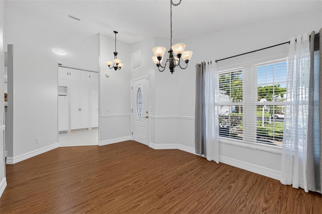 A dining room with wood-look flooring, a chandelier, white walls, and a window with curtains — 4431 FERN DRIVE, BRADENTON, FL
