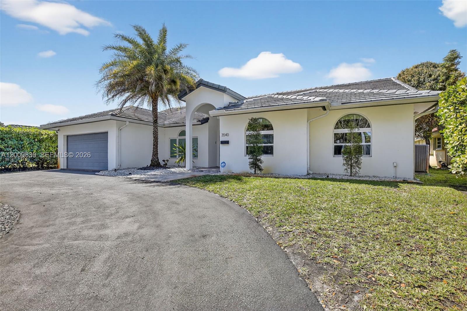 A single-story white house with a gray tile roof, arched windows, and a paved driveway — 3540 N Park Rd, Hollywood FL 33021, HOLLYWOOD, FL