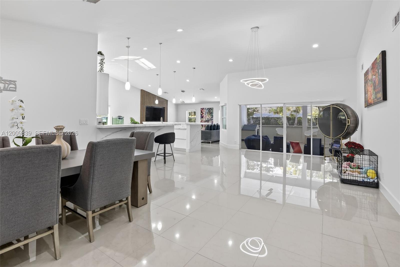 A bright, open-concept living and dining area features white tile floors and modern pendant lighting — 3540 N Park Rd, Hollywood FL 33021, HOLLYWOOD, FL