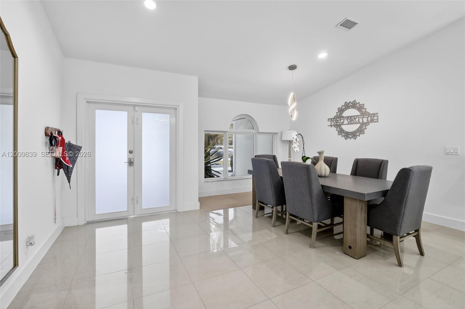 A dining room features a gray table, upholstered chairs, tile flooring, and a double door — 3540 N Park Rd, Hollywood FL 33021, HOLLYWOOD, FL
