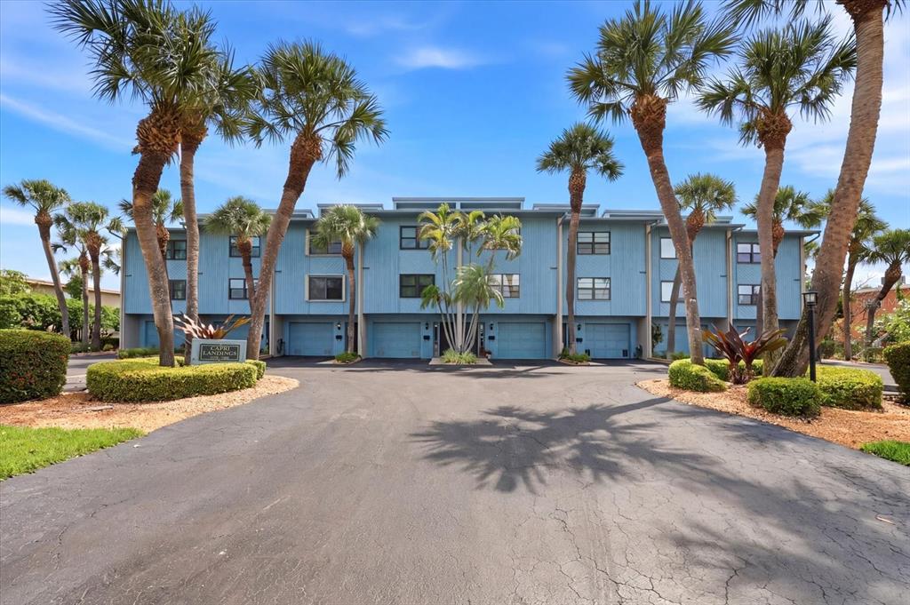 A blue multi-story residential building with palm trees and a paved driveway in front — 11835 3RD STREET E, TREASURE ISLAND, FL