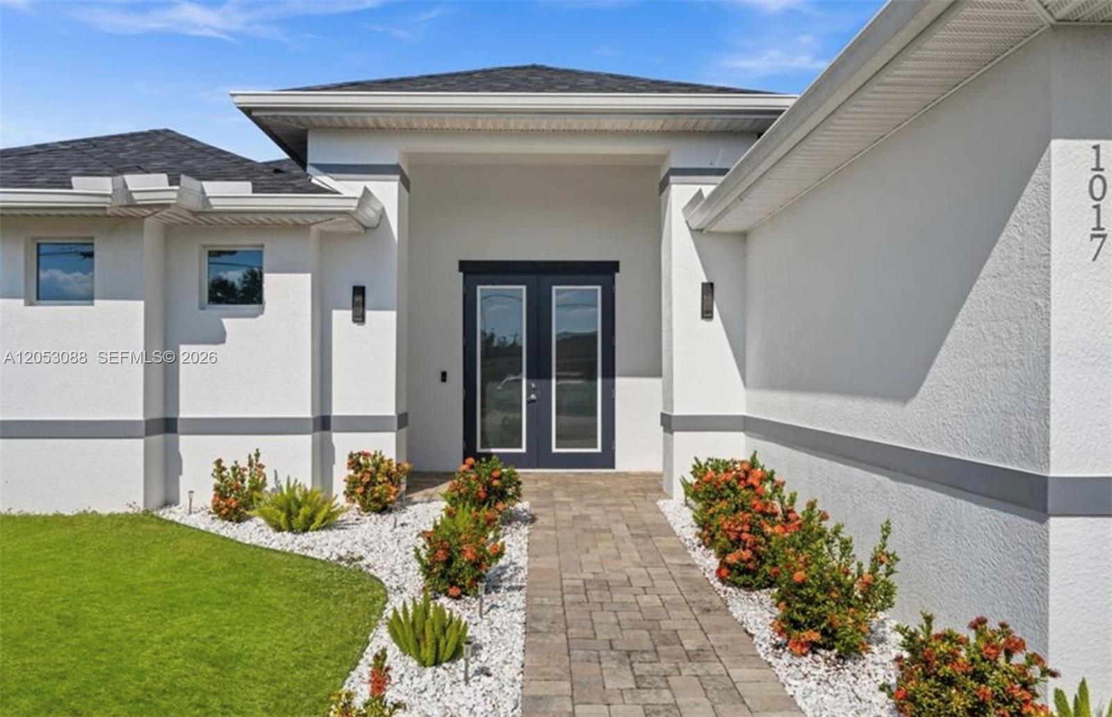 A paved walkway leads to the double front doors of a white stucco house — 1017 NW 15th ter, Cape Coral FL 33993, CAPE CORAL, FL