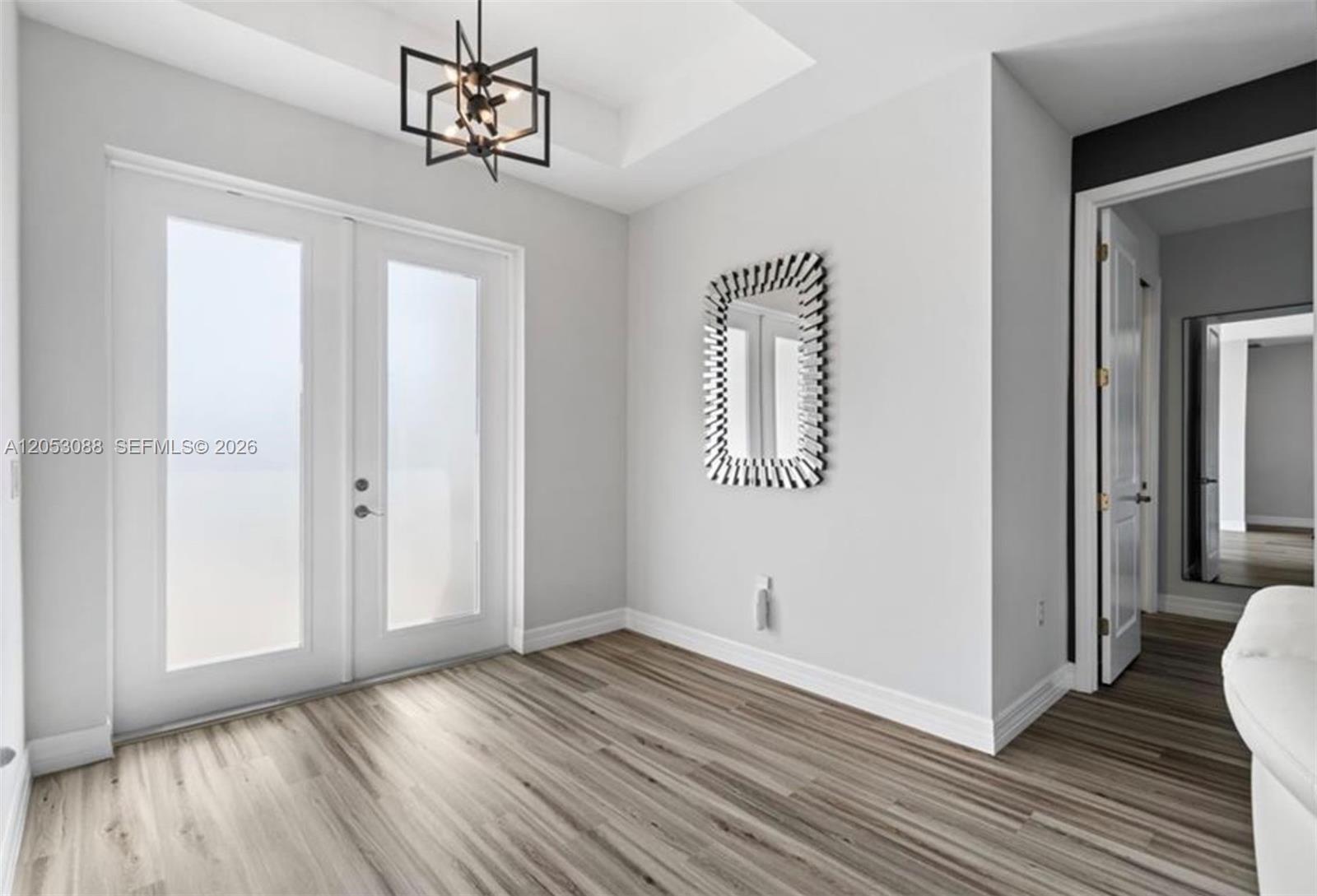A bright entryway features wood-look flooring, a modern chandelier, and a decorative wall mirror — 1017 NW 15th ter, Cape Coral FL 33993, CAPE CORAL, FL