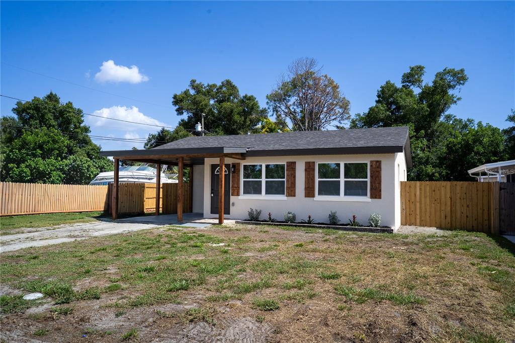 A single-story house with a covered carport, beige siding, and wooden shutters — 5460 77TH AVENUE N, PINELLAS PARK, FL