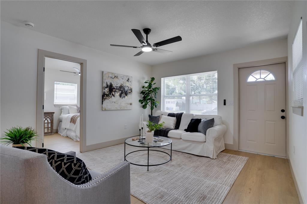 A living room features a white sofa, a glass coffee table, and a ceiling fan — 5460 77TH AVENUE N, PINELLAS PARK, FL