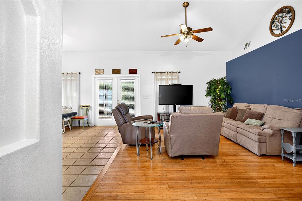 A living room features hardwood floors, a blue accent wall, and a ceiling fan — 2689 SUNBURY ST, CLERMONT, FL