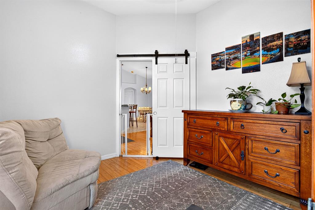 A room features a beige armchair, a wooden dresser, and a sliding barn door — 2689 SUNBURY ST, CLERMONT, FL