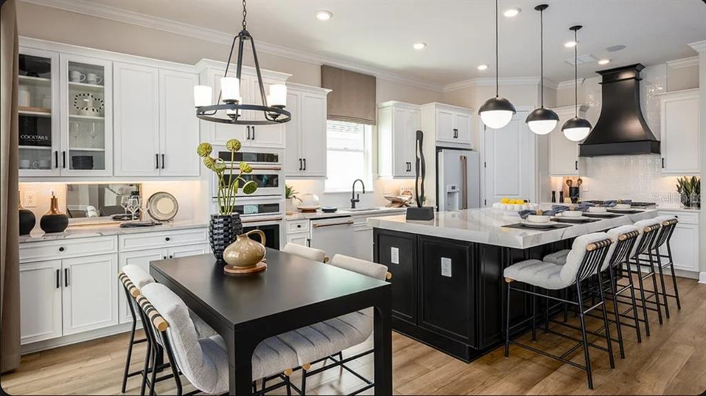 A modern kitchen features white cabinetry, a large black island, and a matching dining table — 11192 CARDING MILL LANE, WINTER GARDEN, FL