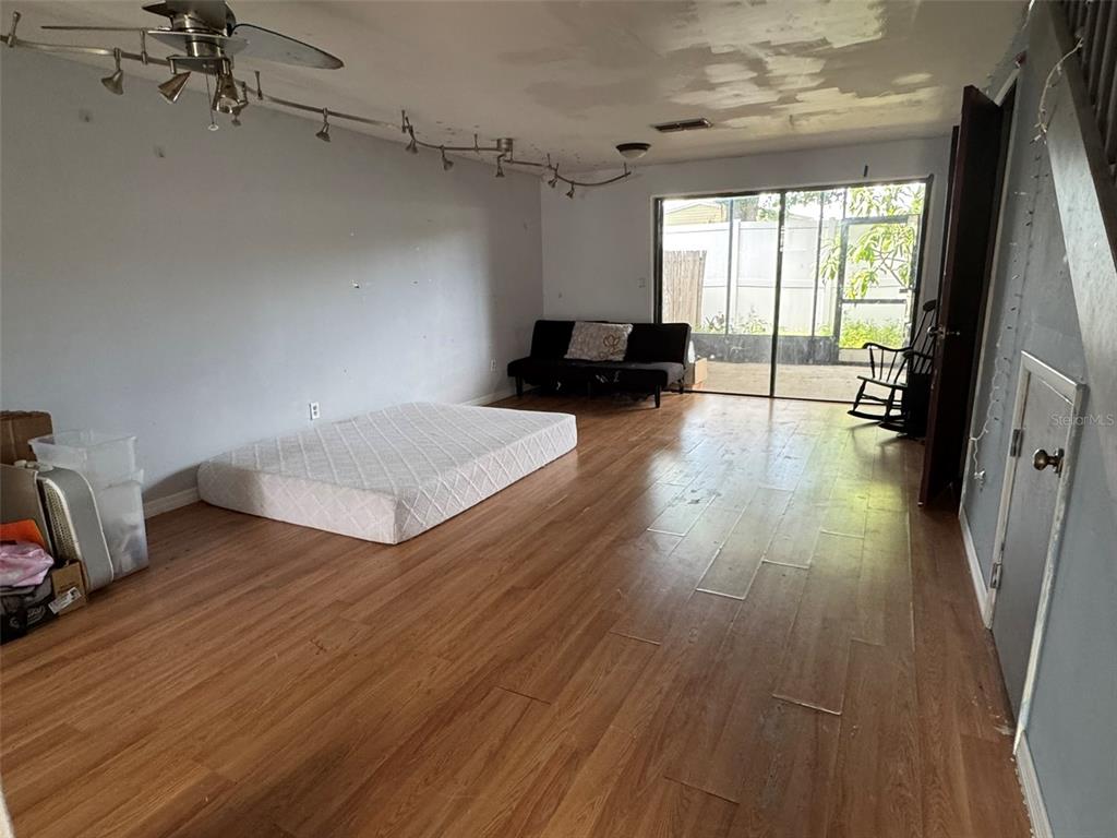 A sparsely furnished room features wood-look flooring, a mattress on the floor, and sliding glass doors — 2811 S PINES DRIVE UNIT 18, LARGO, FL