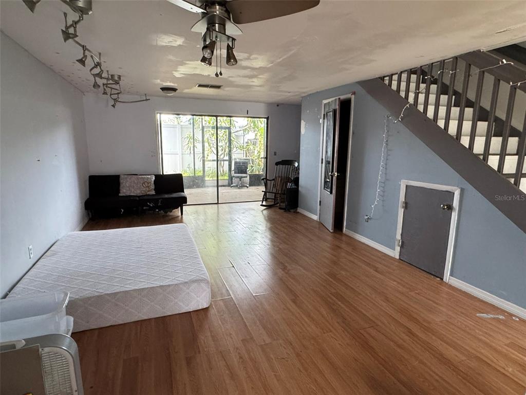 A living room features wood-look flooring, a staircase, a ceiling fan, and a sliding glass door — 2811 S PINES DRIVE UNIT 18, LARGO, FL