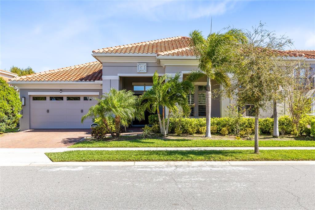 A single-story house with a tiled roof, a two-car garage, and palm trees in front — 13319 ALDERLEY DRIVE, ORLANDO, FL