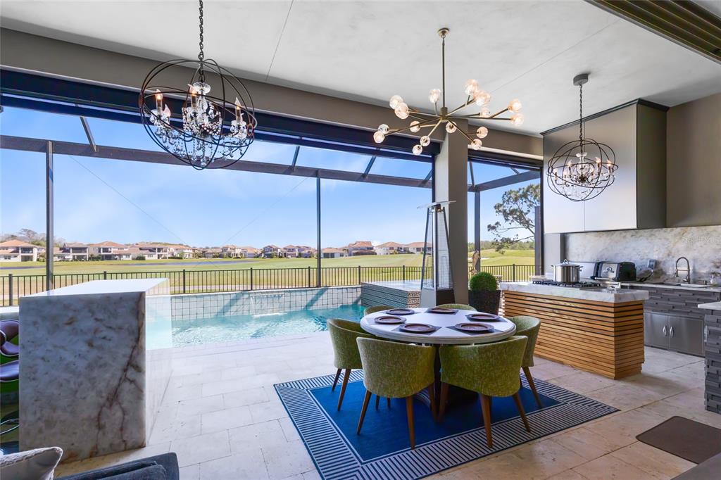 An outdoor covered patio features a dining area, pool, and kitchen overlooking a golf course — 13319 ALDERLEY DRIVE, ORLANDO, FL
