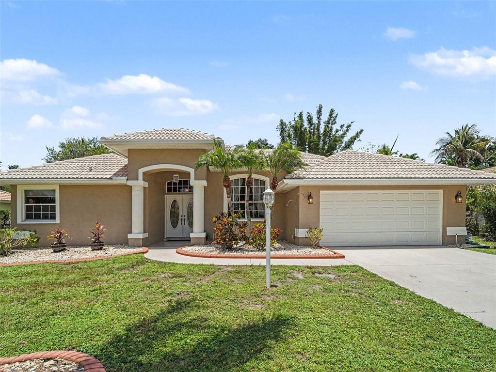 A single-story house with a beige stucco exterior, a tiled roof, and a two-car garage — 4049 GIANNINI LANE, SARASOTA, FL