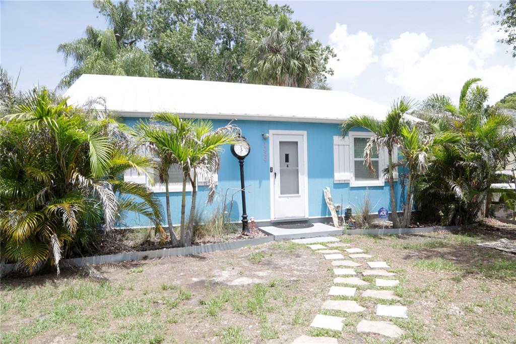 A light blue cottage with a white roof, white shutters, and a stone walkway — 1999 N BETTY LANE, CLEARWATER, FL