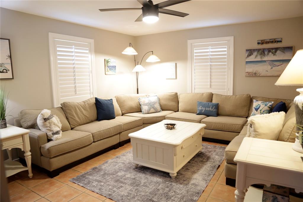 A living room features a large beige sectional sofa, a white coffee table, and a rug — 1999 N BETTY LANE, CLEARWATER, FL