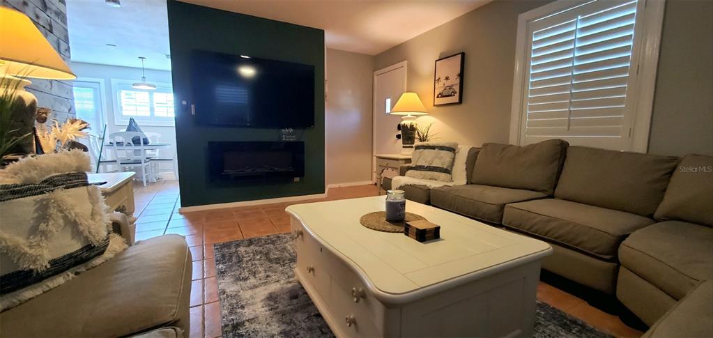 A living room features a dark accent wall with a mounted television and fireplace — 1999 N BETTY LANE, CLEARWATER, FL