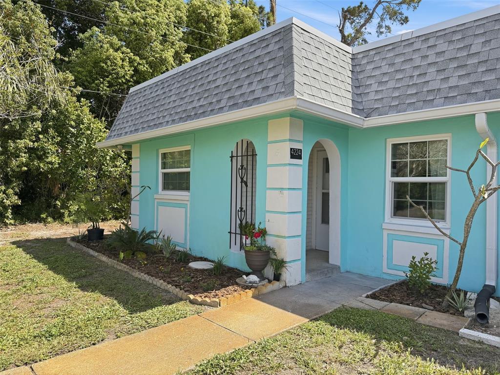 A turquoise house with a gray mansard roof features a white arched entryway and landscaping — 4224 TERRAPIN PLACE UNIT 4224, NEW PORT RICHEY, FL