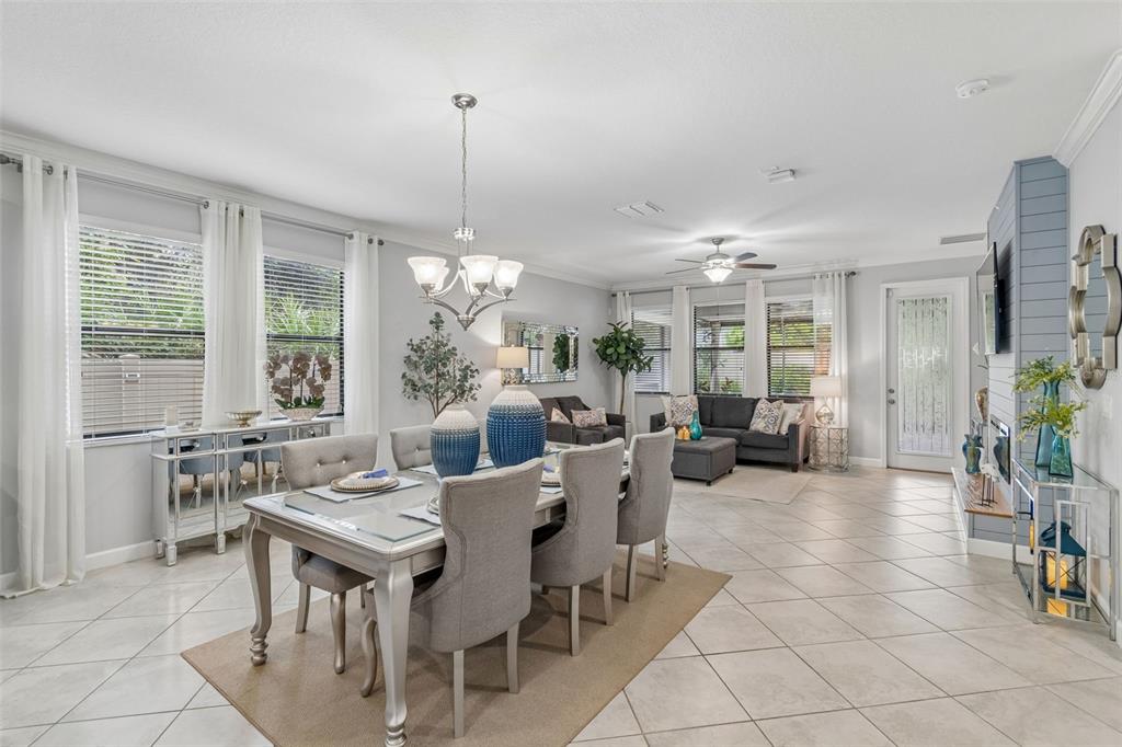 An open-concept dining and living area features tile flooring, neutral walls, and modern furniture — 11002 LITTLE BLUE HERON DRIVE, RIVERVIEW, FL