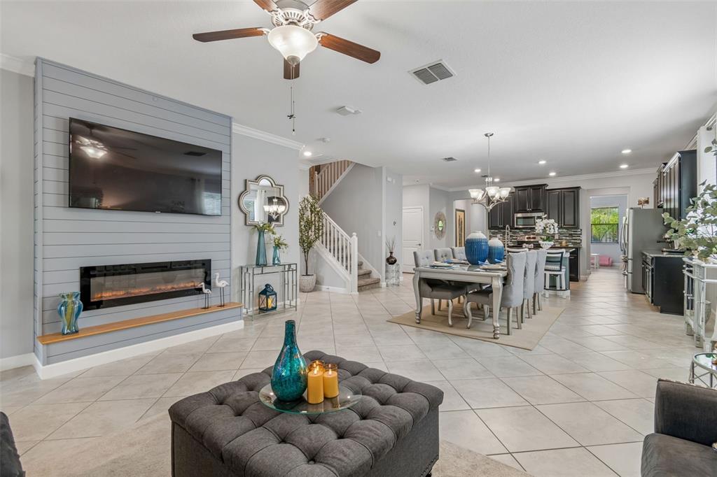 An open-concept living and dining area features a shiplap fireplace wall and tile flooring — 11002 LITTLE BLUE HERON DRIVE, RIVERVIEW, FL