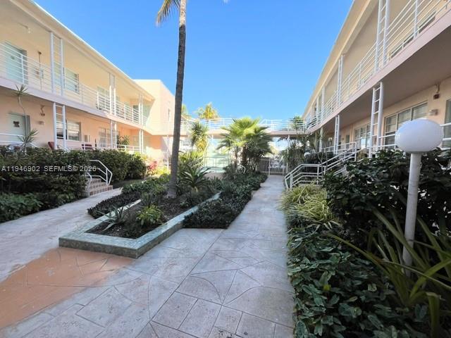 A paved walkway leads between two multi-story apartment buildings with palm trees and landscaping — 6881 Bay Dr # 1, Miami Beach FL 33141, MIAMI BEACH, FL