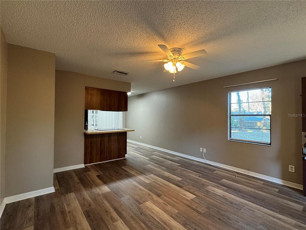 An open living area features wood-look flooring, a ceiling fan, and a kitchen breakfast bar — 5619 PEACH AVENUE, SEFFNER, FL