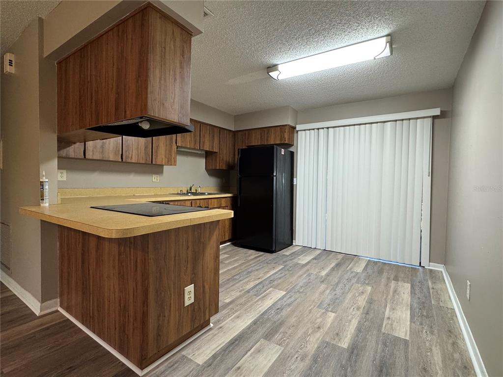 A kitchen features wood-grain cabinets, laminate countertops, black appliances, and wood-look flooring — 5619 PEACH AVENUE, SEFFNER, FL