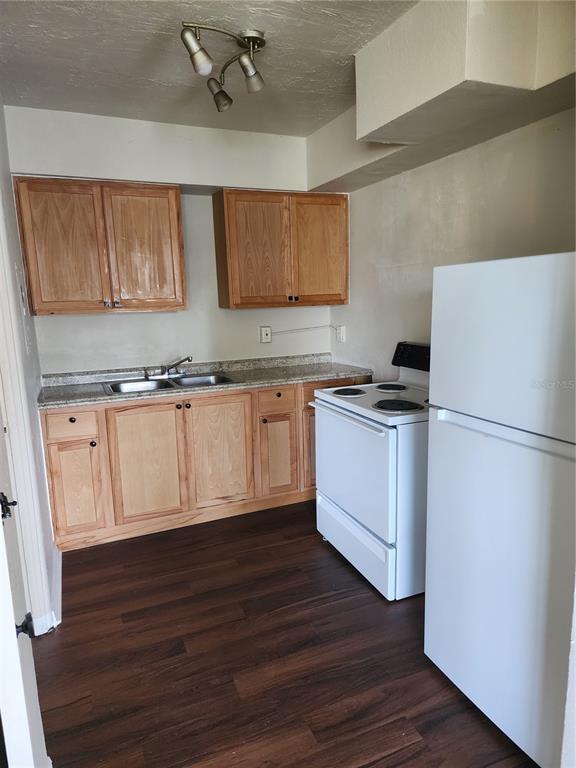 A small kitchen features wood cabinets, a white stove, a refrigerator, and dark wood flooring — 2219 HIGHLAND STREET UNIT 3, ST PETERSBURG, FL