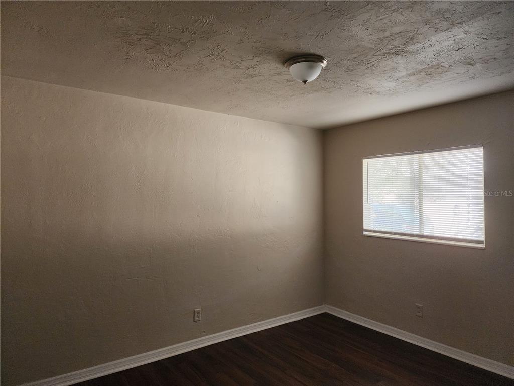 An empty room features beige walls, dark wood-look flooring, and a single window with blinds — 2219 HIGHLAND STREET UNIT 3, ST PETERSBURG, FL